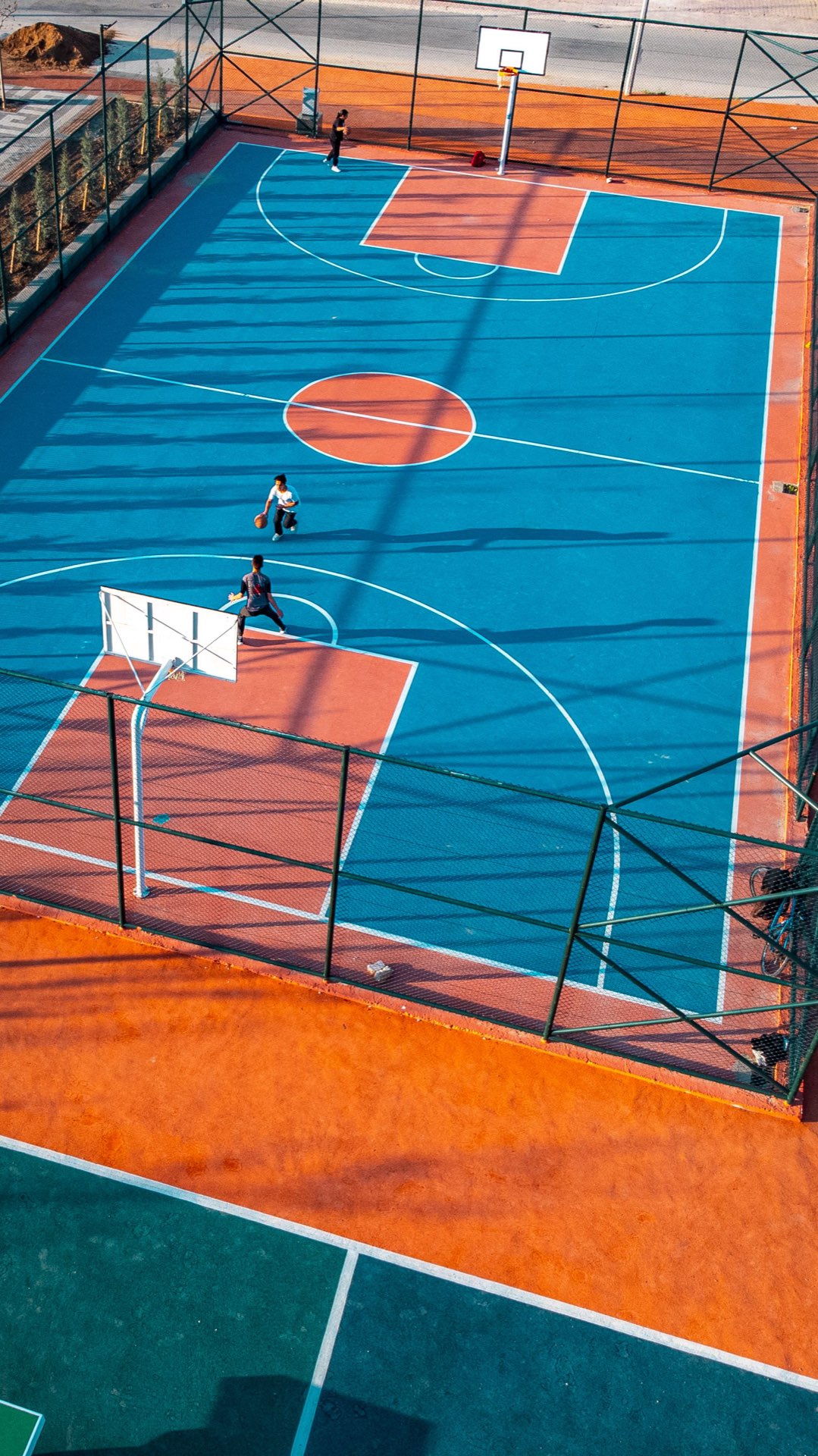 Players on an outdoor basketball court seen from above