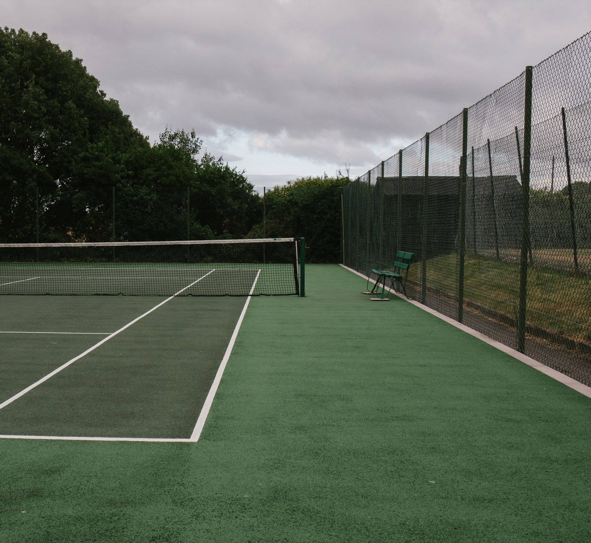 Outdoor tennis court under an overcast sky
