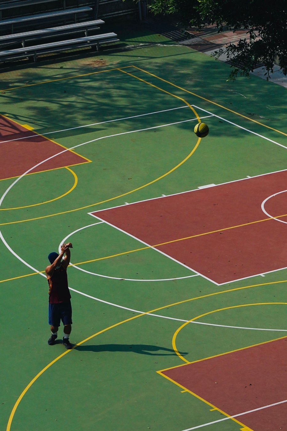 A player shooting on an outdoor basketball court, seen from above