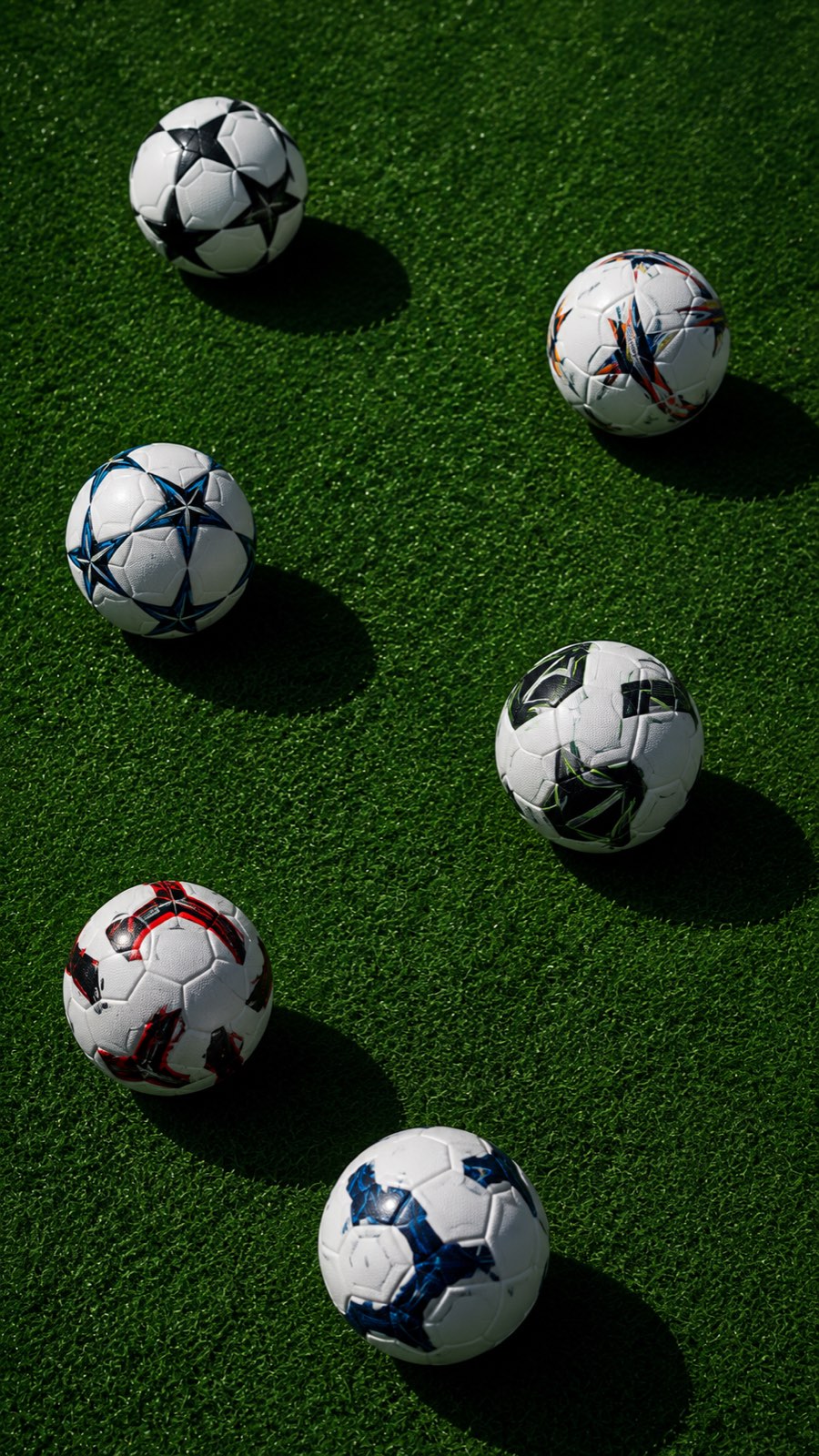 Footballs laid out on artificial turf, ready for a group session